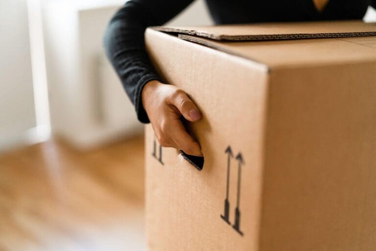 A close-up of a person's hand holding a box meant for moving.