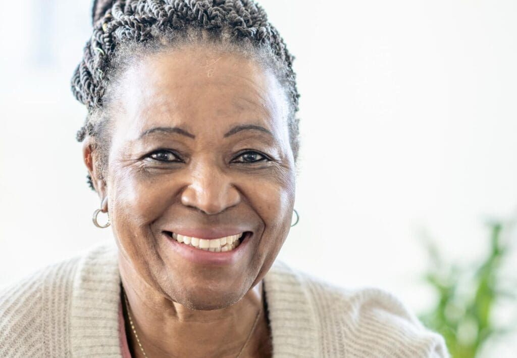 An older adult woman smiles at the camera.